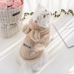 Pisică purtând haină pufoasă bej cu glugă din fleece