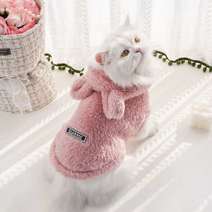 Pisică purtând haină pufoasă roz cu glugă din fleece